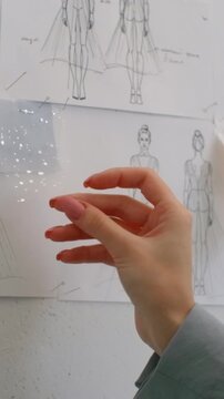 Delicate bridal gown design sketches with transparent fabric swatches and sparkling details carefully reviewed by hands in a fashion design studio workspace
