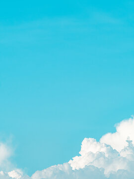 Minimalist bright cyan blue sky with a fluffy white cumulus cloud in the corner, clean summer sky background with large copy space