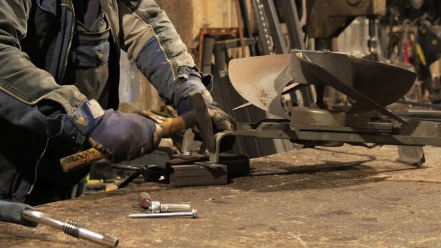 Blacksmith bending metal with hammer and anvil in workshop