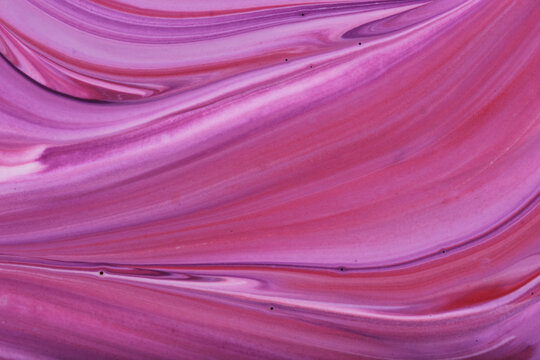 Abstract acrylic fluid art background with smooth waves pink, magenta and violet swirling paint.