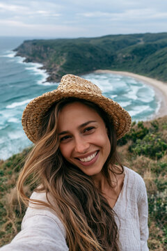 Selfie on the Coast of Oceania smiling young woman wearing straw hat overlooking beautiful beach during relaxing holiday escape