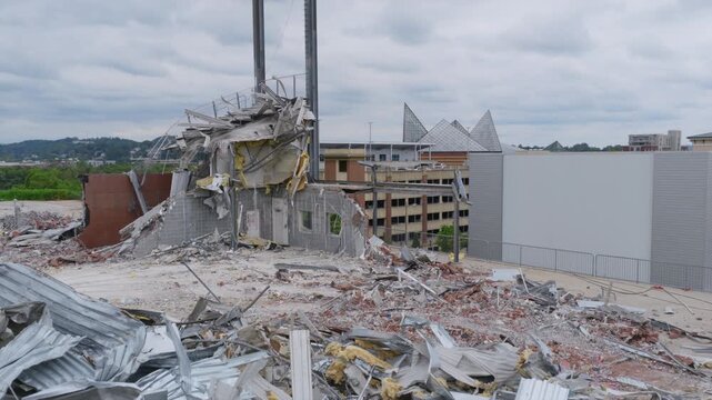 Drone view of the partially demolished ATT Field with light towers standing over rubble, and the Tennessee Aquarium&rsquo;s glass peaks visible in downtown Chattanooga.