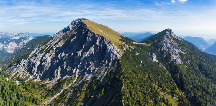 Massive rock face with scenic view of mountain peak TAC Spitze, Hochschwab Alps, Styria, Austria. Steep rocky cliffs with man.