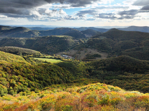 Scenic aerial view of a winding mountain by autumn forest colours and small village in Slovakia