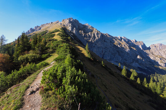 Massive rock face with scenic view of mountain peak TAC Spitze, Hochschwab Alps, Styria, Austria. Steep rocky cliffs with man.