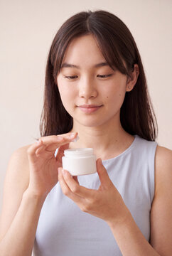 Woman applying face cream from a jar for skincare routine and beauty product background or cosmetic banner use