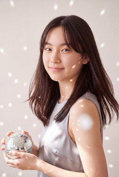 Young woman holding disco ball with reflected light dots for party background and festive portrait banner