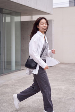 Young woman walking outdoors in casual outfit with crossbody bag for urban lifestyle background and motion banner design