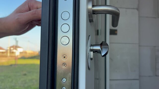Close-up of hand opening a modern heavy-duty security door with multiple locking bolts. home security, safety, construction, real estate, and modern building technology.