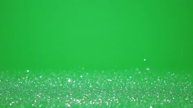 A textured surface composed of sparkling green particles against a solid, similarly colored background