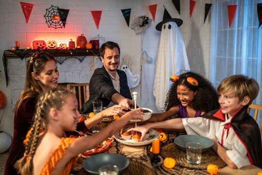 Multiracial family celebrating Halloween party together in house.