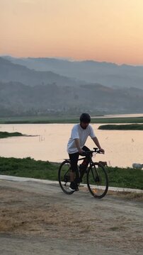 Cyclist Resting by Lake at Sunset