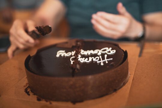 Person taking the first slice of chocolate cake