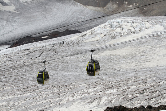 Two cable cars ascend over a vast glacier