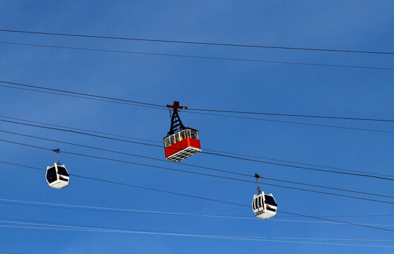 Vintage red cable car and modern gondolas against a blue sky