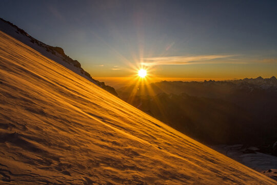 Golden sunrise illuminates a snowy mountain slope