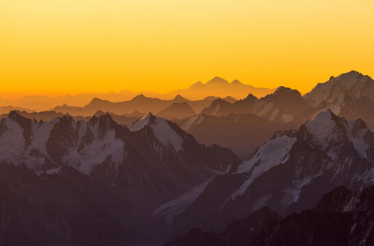 Golden sunrise over hazy snow covered mountains