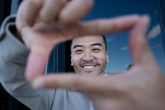 Man framing face with hands and smiling outdoors in Madrid, Spain