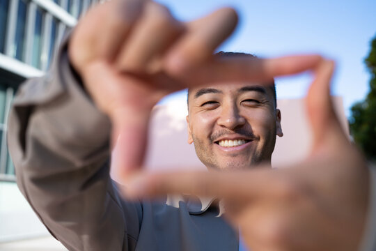 Man smiling framing gesture outdoors under blue sky