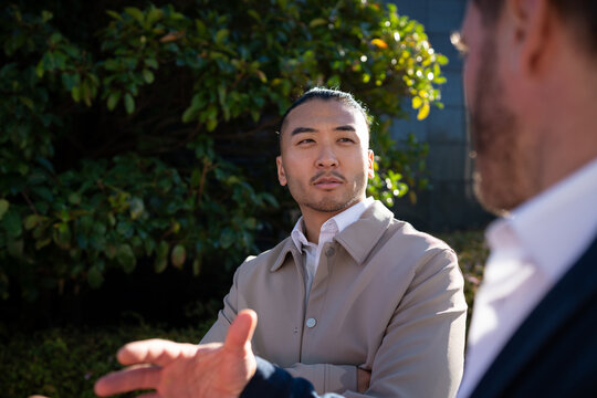 White man with bun listening during outdoor conversation