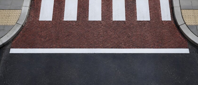 Red high friction polyurethane aggregate surfacing on road approach to pedestrian crossing