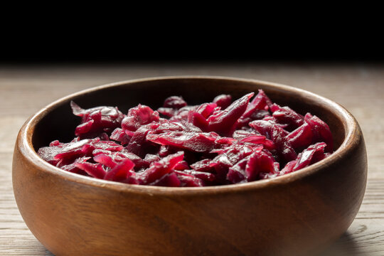 Red cabbage, braised in red wine with apple, in a brown wood bowl background backdrop. On a wooden chopping board.