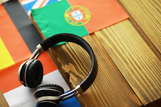 International Language Learning Concept with Headphones on World Flags Background