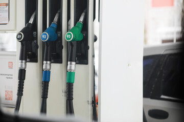Fuel Pump Nozzles at Gas Station with Price Displays and Cars in Background © alexkich