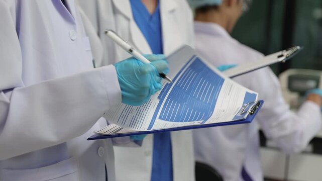 Female scientists analyzing research results on clipboard. Two female research scientists in a laboratory discussing and writing down experiment data.
