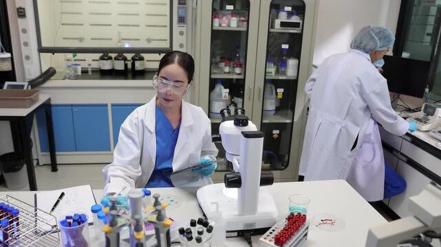 Young female scientist conducting medical research in a laboratory, working with test tubes and a microscope in a modern research facility.
