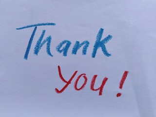 Hand-written "Thank You!" text on white paper with blue and red crayon © Putu