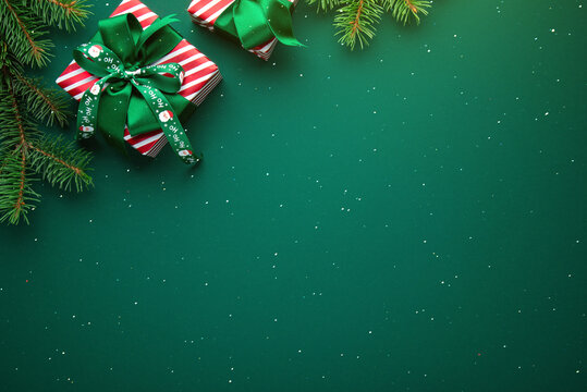 Green Christmas and Happy New Year holiday background with gift boxes, green ribbon bows and festive ornaments, flat lay with copy space. Greeting card.