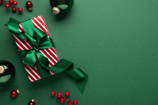 Green Christmas and Happy New Year holiday background with gift boxes, green ribbon bows and festive ornaments, flat lay with copy space. Greeting card.