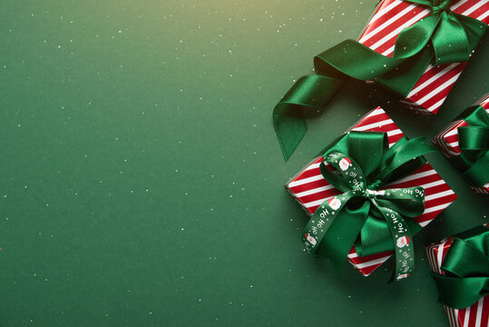 Green Christmas and Happy New Year holiday background with gift boxes, green ribbon bows and festive ornaments, flat lay with copy space. Greeting card.