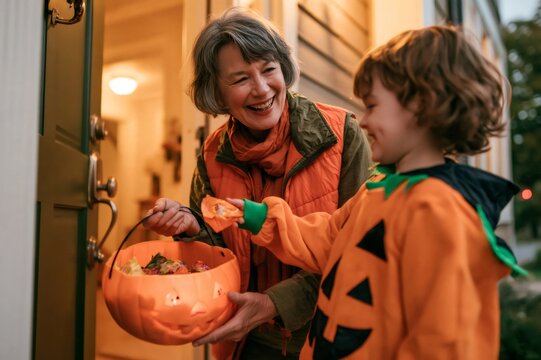 Grandmother giving candy to boy in pumpkin costume