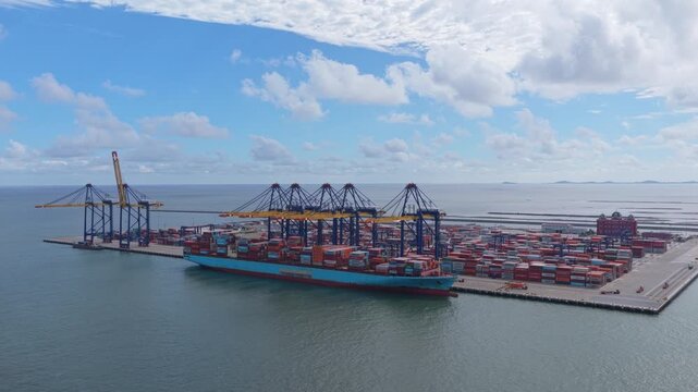 Scenic aerial footage of a large cargo vessel docked at the industrial seaport in hai phong, vietnam, with cranes loading containers