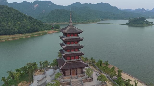Drone circling the pagoda zoe mascot in vietnam. Majestic buddhist temple surrounded by a serene lake and lush green mountains