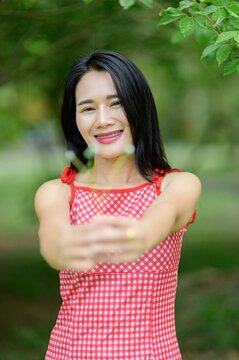 Woman in Red Dress Enjoying Nature in Flower Garden Surrounded by Trees