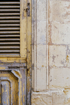 Weathered Yellow Wooden Shutter Door, Peeling Paint, Aged Carved Wood, Limestone Wall Texture