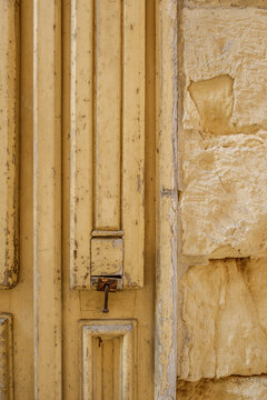 Weathered Yellow Wooden Door Detail and Aged Stone Wall Texture, Vintage Panelled Surface, Distressed Exterior