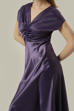 Elegant woman in purple satin midi dress posing in studio