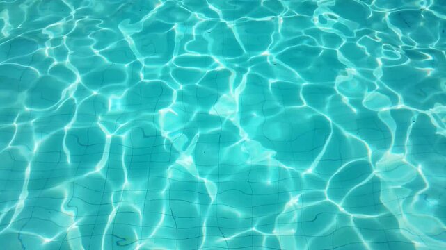 water with gentle ripples and shimmering sunlight reflections dancing across the tiled pool floor. Beautiful patterns of light create a relaxing, refreshing, and tranquil atmosphere. 