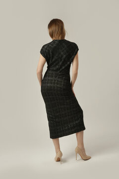 Fashion model wearing a black textured midi dress with a subtle sheen, V neckline and short sleeves, elegant and sophisticated contemporary fall style