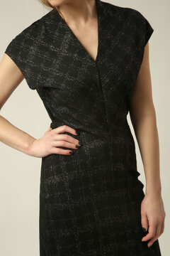 Fashion model wearing a black textured midi dress with a subtle sheen, V neckline and short sleeves, elegant and sophisticated contemporary fall style