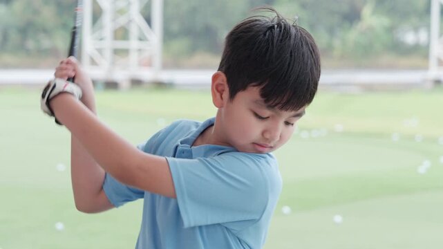 Young Boy Learning Golf and Smiling at Outdoor Driving Range