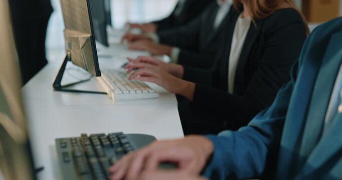 Businessman types on keyboard at workstation while colleagues work nearby. Focused man uses desktop computer handling company task with steady pace on busy day