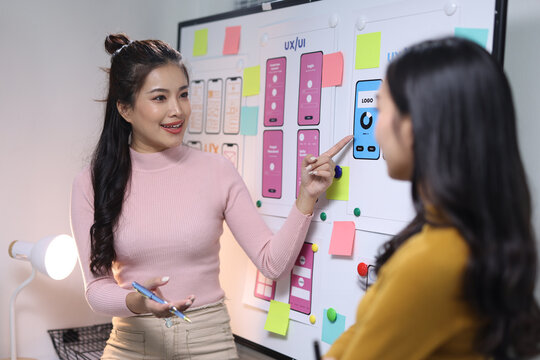 UX designer team brainstorming mobile application interface on whiteboard.