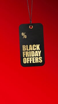 Black friday offers promotional tag with a gold inscription slowly swaying. A black label hanging on a red background for a sales event. Looping video in 3d animation