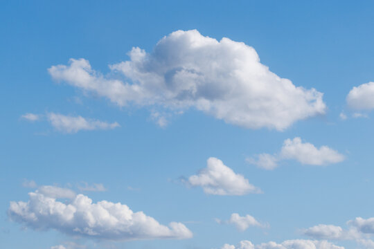 Soft white clouds drift across a bright blue sky