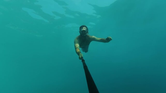 Man Diving and Swimming Underwater With Selfie Stick